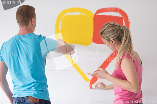 Image of couple are painting a heart on the wall