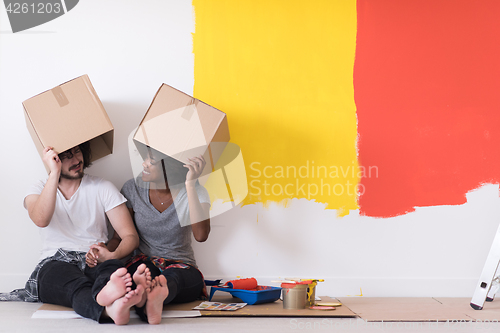 Image of young multiethnic couple playing with cardboard boxes