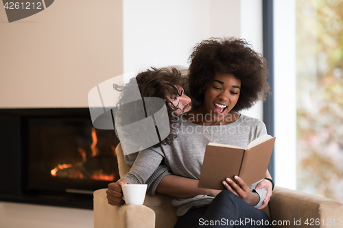 Image of multiethnic couple hugging in front of fireplace
