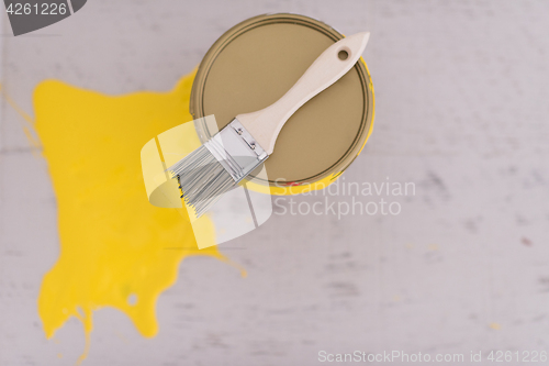 Image of Yellow paint tin can with brush on top