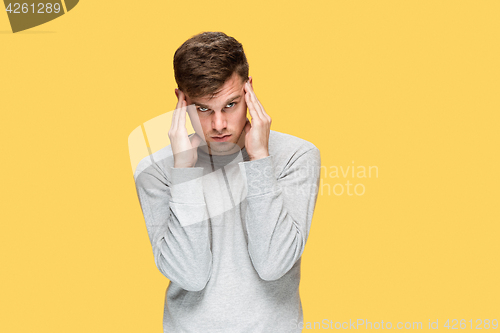 Image of Tired businessman or The serious young man over yellow studio background with headache emotions