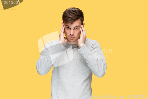 Image of Tired businessman or The serious young man over yellow studio background with headache emotions