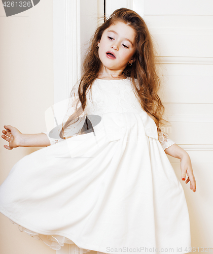 Image of little cute girl at home, opening door well-dressed in white dre