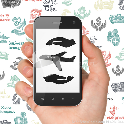 Image of Insurance concept: Hand Holding Smartphone with Airplane And Palm on display