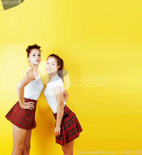 Image of lifestyle people concept: two pretty young school teenage girls having fun happy smiling on yellow background 