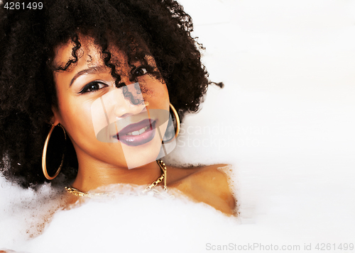 Image of young afro-american teen girl laying in bath with foam, wearing 