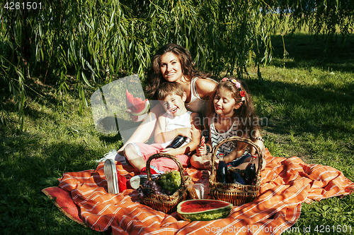 Image of cute happy family on picnic laying on green grass mother and kid