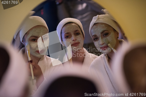 Image of women putting face masks in the bathroom