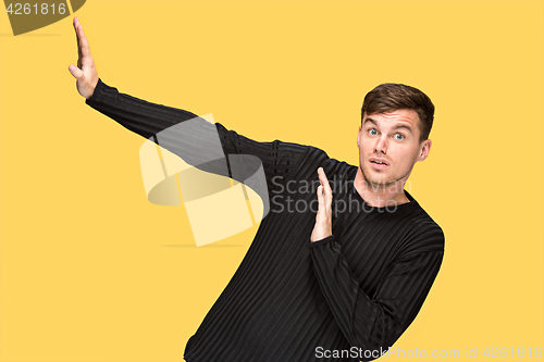 Image of The young man pointing to something and looking at camera