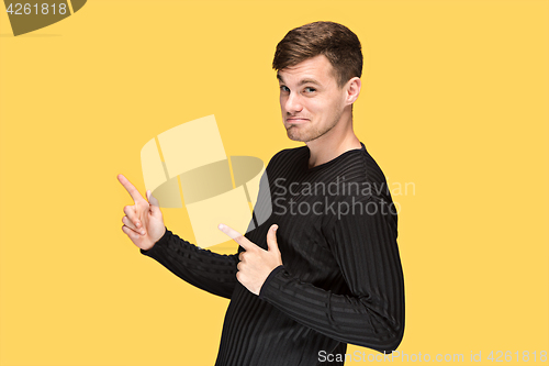 Image of The young man pointing to something and looking at camera