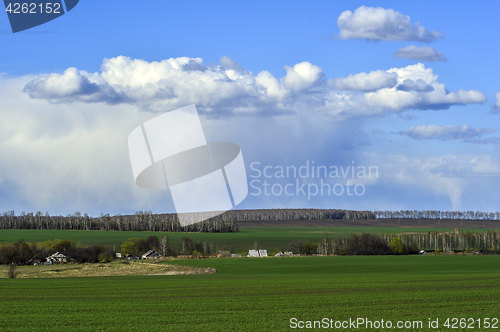 Image of Rural landscape with a green field, clouds and farm