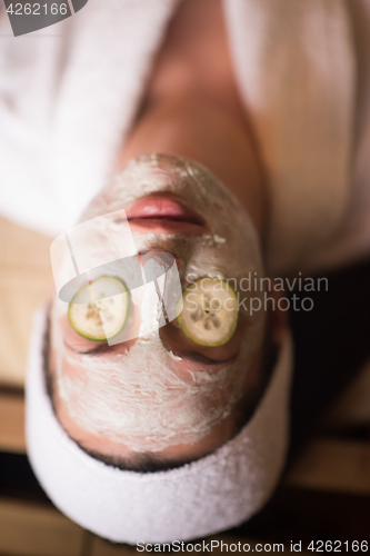 Image of woman is getting facial clay mask at spa