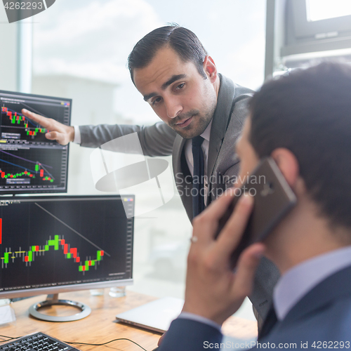 Image of Stock brokers looking at computer screens, trading online.