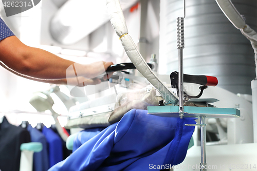 Image of Clothing industry. Ironing steam. Presser in sewing clothes pressed. 