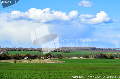 Image of Rural landscape with a green field, clouds and farm