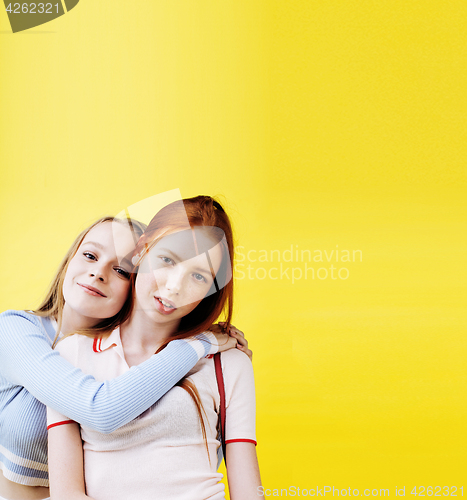 Image of lifestyle people concept: two pretty young school teenage girls having fun happy smiling on yellow background 
