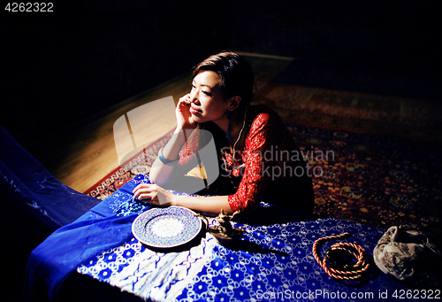 Image of young pretty asian girl in bright colored interior on carpet view, oriental people lifestyle concept