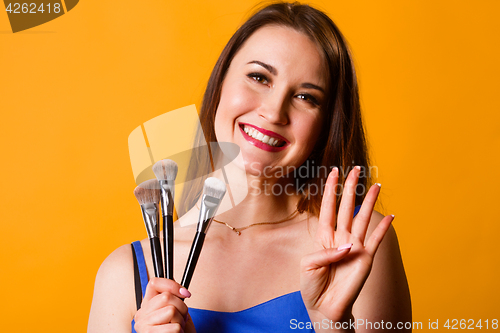 Image of Smiling woman with makeup brushes