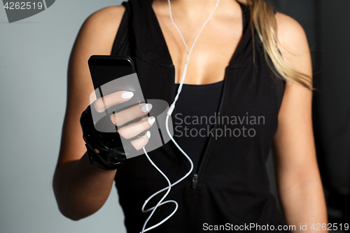 Image of sportswoman with smartphone and earphones