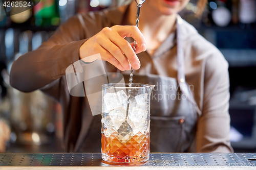 Image of bartender with cocktail stirrer and glass at bar