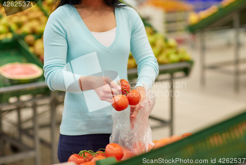 Image of woman with bag buying tomatoes at grocery store