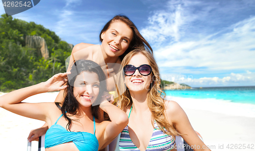 Image of happy women sunbathing on chairs at summer beach