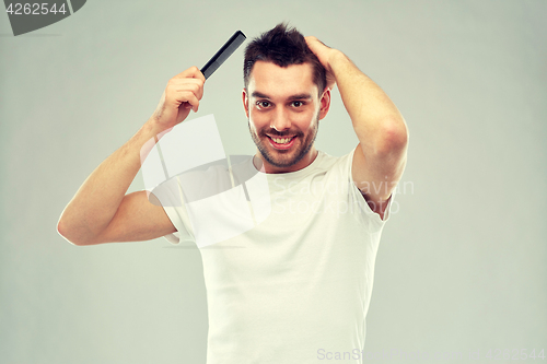 Image of happy man brushing hair with comb over gray