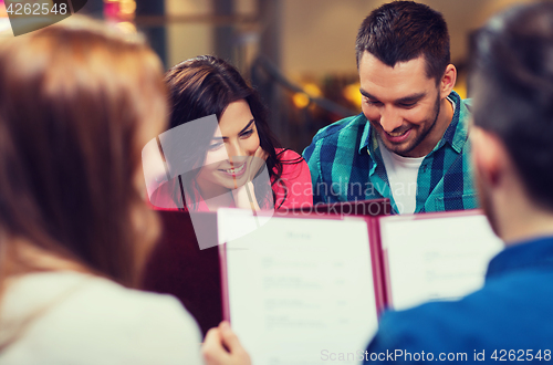 Image of smiling couple with friends and menu at restaurant