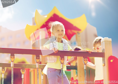 Image of happy little girl climbing on children playground