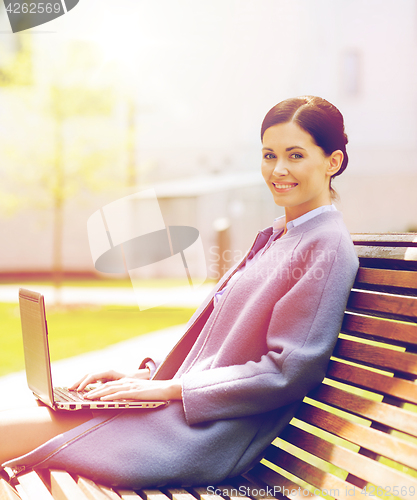 Image of smiling business woman with laptop in city