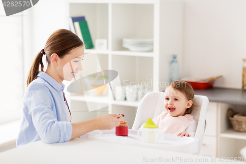 Image of happy mother feeding baby with puree at home