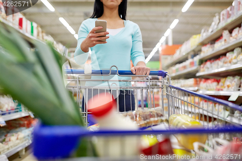 Image of woman with smartphone buying food at supermarket