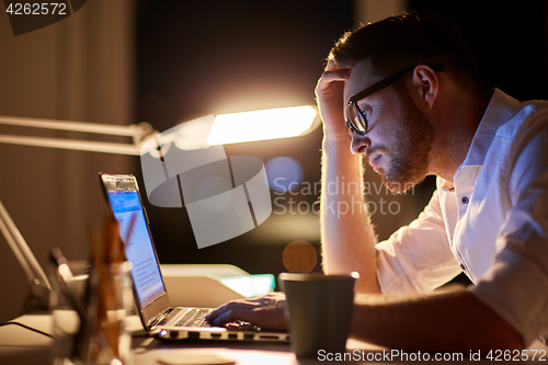 Image of businessman typing on laptop at night office