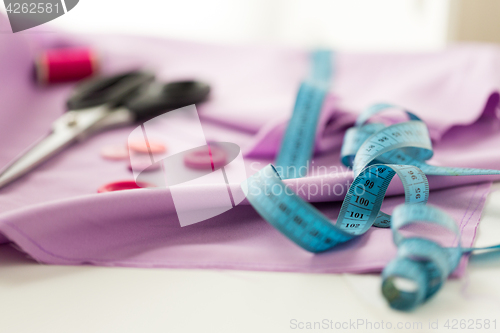 Image of scissors, sewing buttons, tape measure and cloth