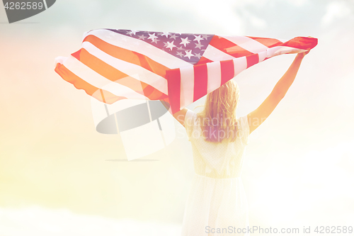 Image of happy young woman with american flag outdoors