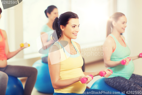 Image of happy pregnant women exercising on fitball in gym