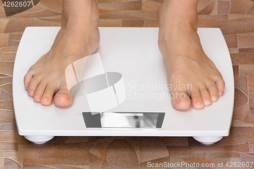 Image of pair of female feet standing on the scale