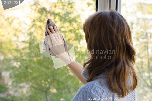 Image of young woman washing window