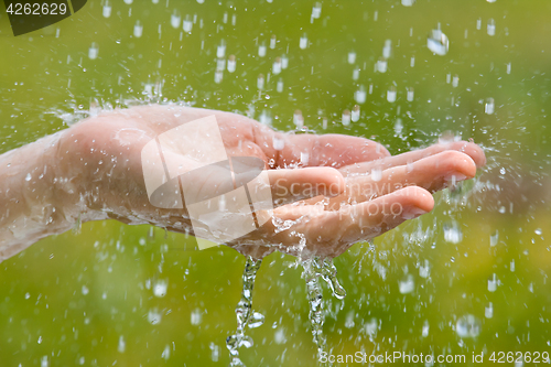 Image of hand of woman catching raindrops, closeup