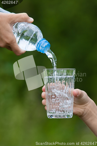 Image of hand pouring water from bottle into glass