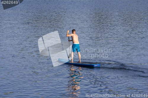 Image of Man on Paddle Board paddling out to lake