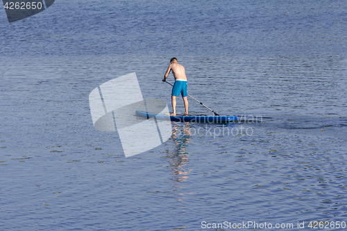 Image of Man on Paddle Board paddling out to lake