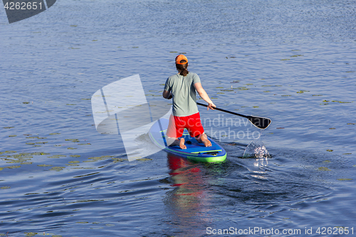 Image of Man on Paddle Board paddling out to lake