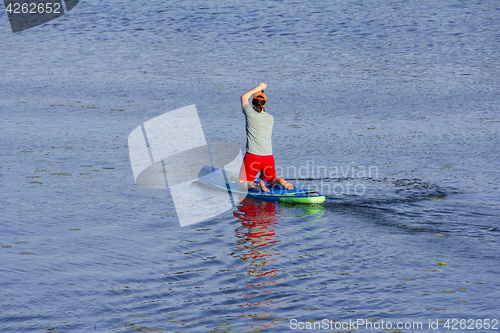 Image of Man on Paddle Board paddling out to lake