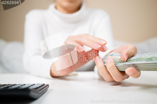 Image of business, finance, saving, banking and people concept - close up of woman hands counting us dollar money