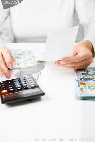 Image of savings, finances, economy and home concept - close up of hands with calculator counting money and making notes at home