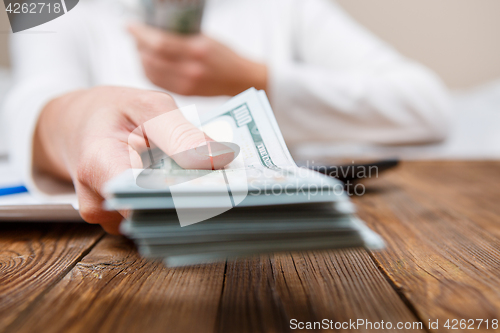 Image of Hands of person proposing money to you - closeup shot