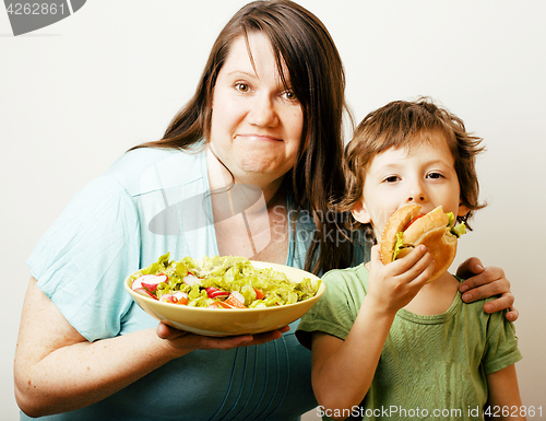 Image of mature woman holding salad and little cute boy with hamburger te