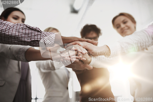 Image of happy business team with hands on top at office