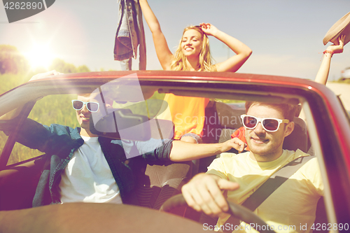 Image of happy friends driving in cabriolet car